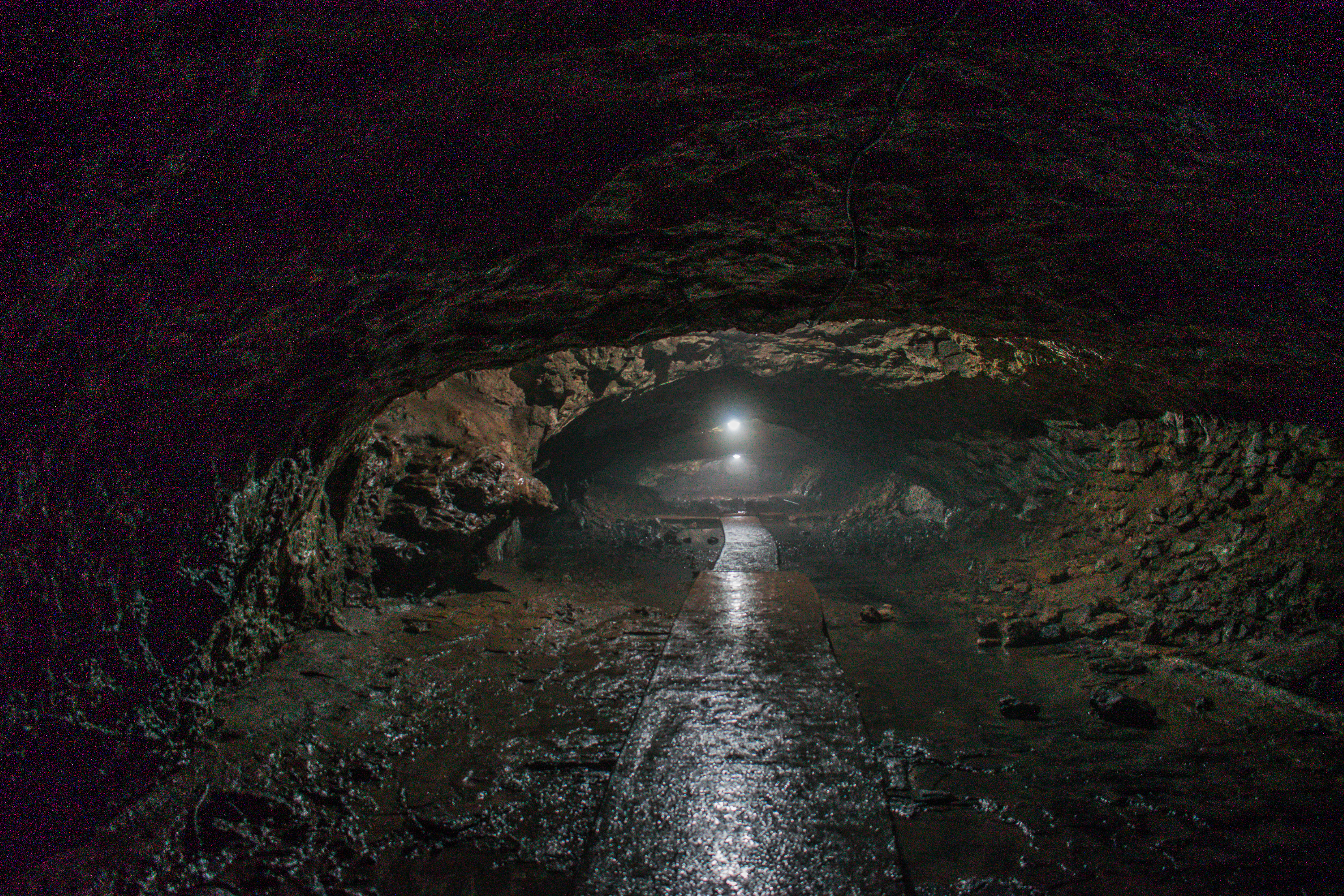 Long cave tunnel with wet floor and distant lights